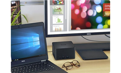 The E5470 is placed on desktop together with a docking station, a pair of glasses, and a Dell monitor.